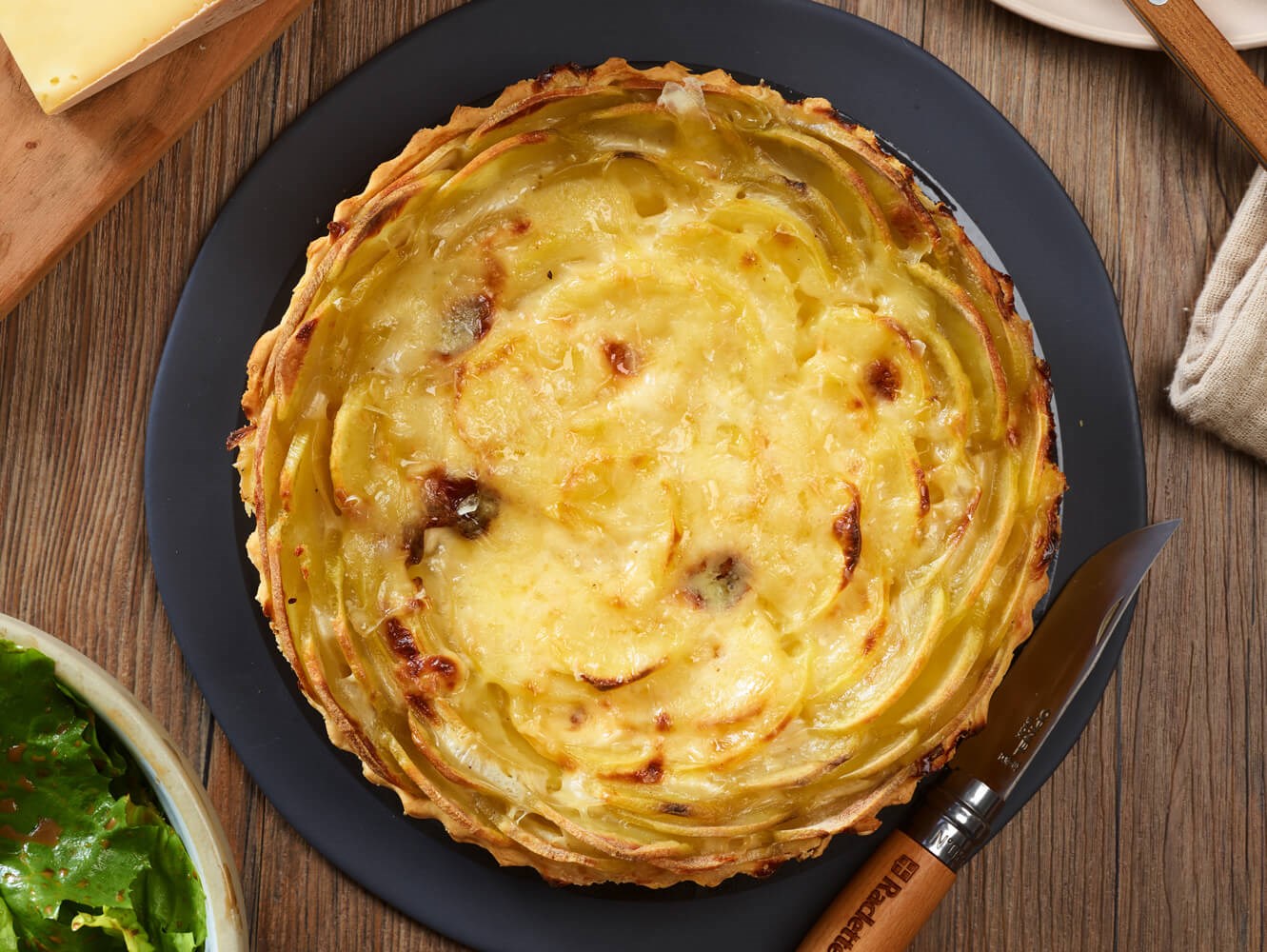 Tarte à la pomme de terre parsemée de Raclette de Savoie.